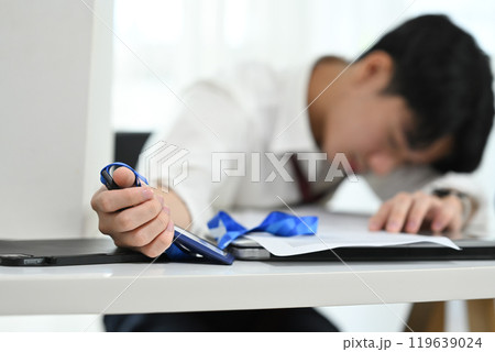 Exhausted office worker falling asleep on his desk. Fatigue in the workplace concept 119639024