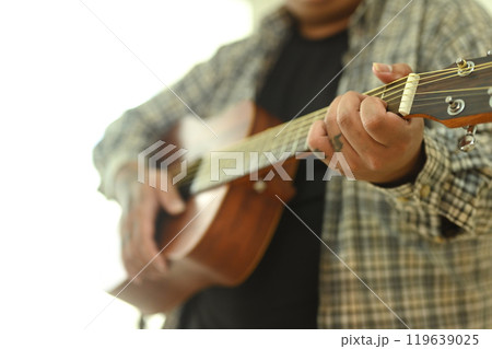 Close up of man practicing acoustic guitar chords. Leisure activity and hobby concept 119639025