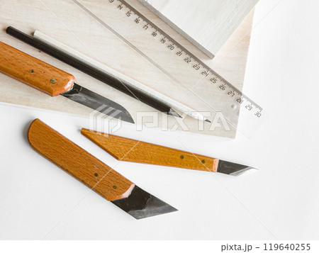 Crafting essentials. Precision knives, ruler, and pencil on wooden surface 119640255