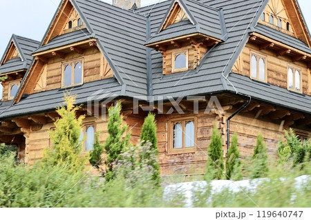 Three-story wooden beige house with complex roof structure. 119640747
