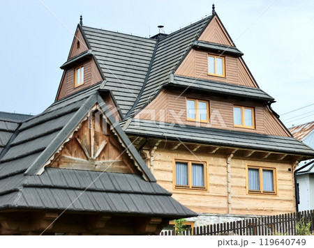 Three-story wooden beige house with complex roof structure. 119640749