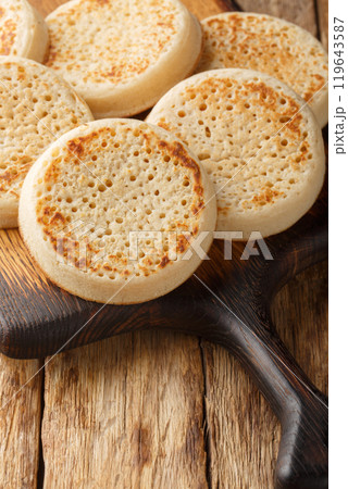 Crumpets fresh from a bakery closeup on the wooden board. Vertical 119643587