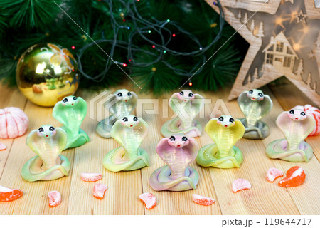 Snake - handmade soap, symbol of the future 2025. Christmas-style composition against the background of garlands and fir-tree branches Snake - handmade soap, symbol of the future 2025. Christmas-style composition against the background of garlands and fir-tree branches 119644717