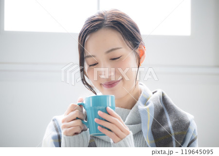 部屋で温かいコーヒーや飲み物を飲むかわいい女性 俯く目を閉じるクローズアップ　秋冬のリラックスする 119645095