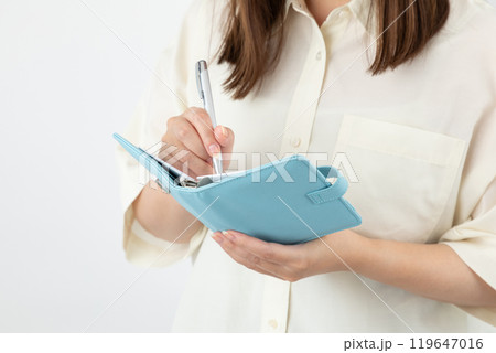 手帳に書き込む女性01 119647016