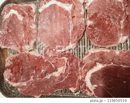 Raw rib eye steak cooking on the griddle. Close up red meat 119650559