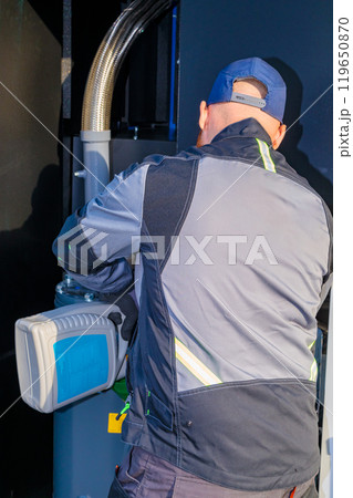 Technician Filling Oil into Industrial Screw Compressor Technician Filling Oil into Industrial Screw Compressor 119650870