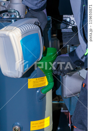 Technician pouring oil into industrial compressor using funnel Technician pouring oil into industrial compressor using funnel 119650871