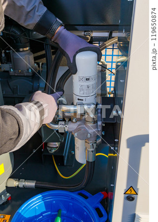 Technician replacing oil filter in industrial air compressor system Technician replacing oil filter in industrial air compressor system 119650874