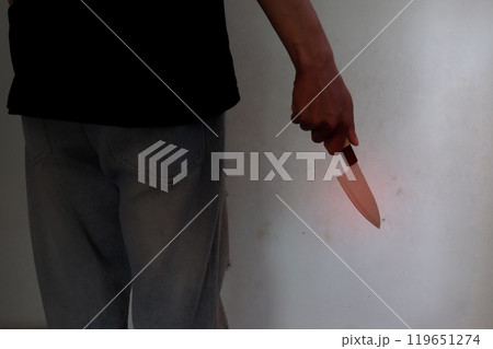 Person wears blue jeans holding kitchen knife by hand . Person wears blue jeans holding kitchen knife by hand . 119651274