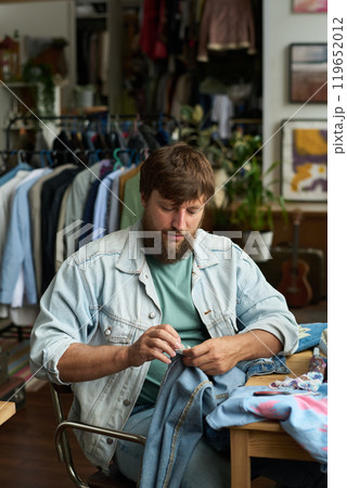 Bearded man upcycling secondhand jeans Bearded man upcycling secondhand jeans 119652012