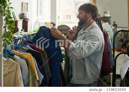 Taking hanger with blue shirt from rack 119652039