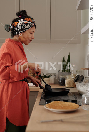 Hispanic Woman Cooking Pancakes on Stove in Kitchen 119652205
