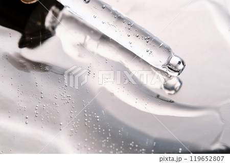 Dropper pipette with delicious serum with bubbles on the gel texture. Dropper pipette with delicious serum with bubbles on the gel texture. 119652807