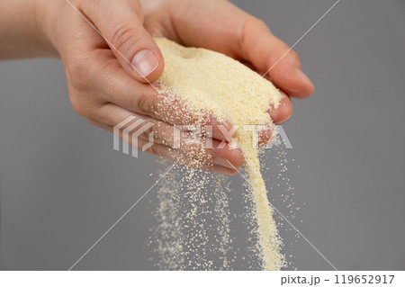 Hands pouring dry semolina durum flour uncooked organic semolina close-up gray background Hands pouring dry semolina durum flour uncooked organic semolina close-up gray background 119652917