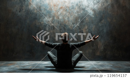 Young man sitting in yoga pose meditating in front of grunge wall Young man sitting in yoga pose meditating in front of grunge wall 119654137