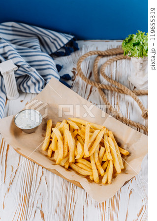 Golden French fries with a side of creamy dip, perfect for snack lovers 119655319