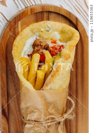 Delicious pita wrap with chicken, fries, fresh vegetables, and tzatziki, quick meal or takeaway Delicious pita wrap with chicken, fries, fresh vegetables, and tzatziki, quick meal or takeaway 119655363