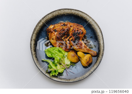 Juicy roasted chicken with black pepper, grilled potatoes, and fresh greens, elegantly plated 119656040