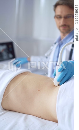 Doctor man wearing blue protective gloves is using ultrasound equipment on the back of a patient, woman. Medicine service 119656083