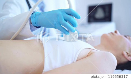 Doctor man, wearing blue medical gloves, is using ultrasound machine to examine internal organs of a patient woman, close up vie. Female mammary gland health. Medicine Doctor man, wearing blue medical gloves, is using ultrasound machine to examine internal organs of a patient woman, close up vie. Female mammary gland health. Medicine 119656317