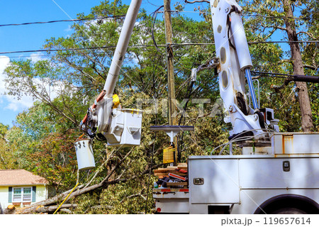 After hurricane, technician works on an electrical pole using bucket lift After hurricane, technician works on an electrical pole using bucket lift 119657614