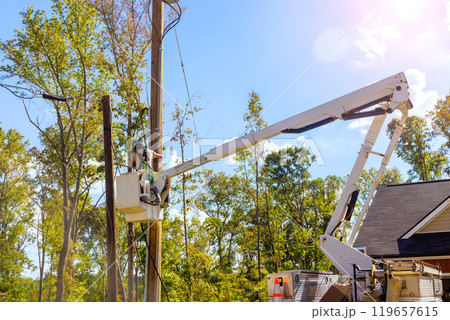 Lineman performing overhead electrical maintenance using bucket lift truck 119657615