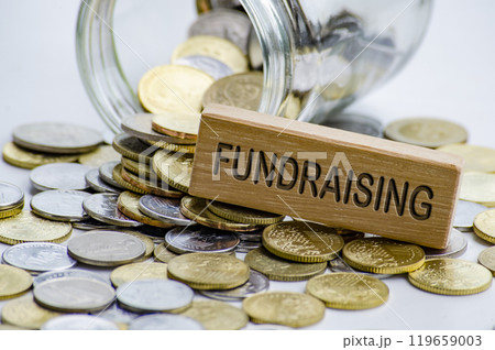 Fundraising text on wooden block with coins and jar background. Charity concept Fundraising text on wooden block with coins and jar background. Charity concept 119659003
