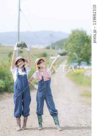 収穫した野菜を持って歩く若い女性達 119662310