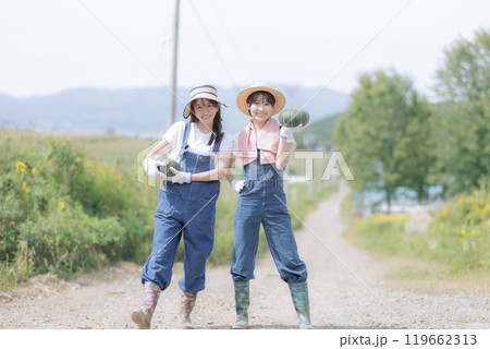 収穫した野菜を持って歩く若い女性達 119662313