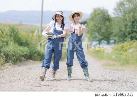 収穫した野菜を持って歩く若い女性達 119662315