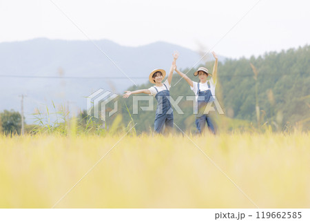 田んぼ越しに手を振る若い女性達 119662585
