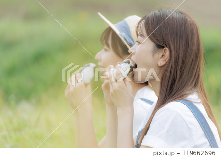 稲刈りの途中で休憩をしている若い女性達 119662696