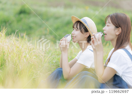稲刈りの途中で休憩をしている若い女性達 119662697