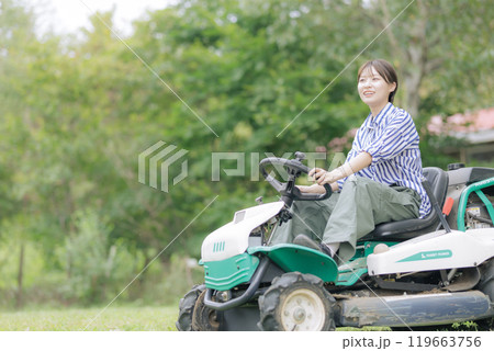 芝刈り機に乗る若い女性 119663756