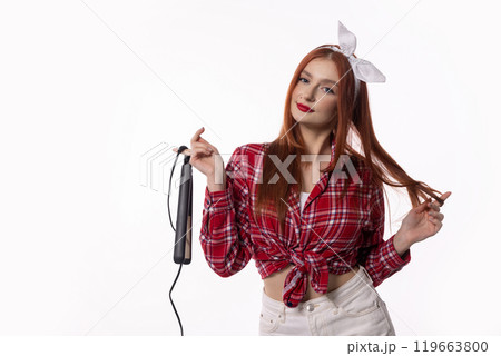 A Stylish Woman Holding a Hair Straightener, Dressed in a Chic Retro Outfit, Exuding Elegance A Stylish Woman Holding a Hair Straightener, Dressed in a Chic Retro Outfit, Exuding Elegance 119663800