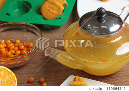 Sea buckthorn, orange and spice tea from frozen briquette in teapot in kitchen. Healthy eating and seasons. Quick batch of beverages. 119664341