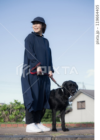 青空の中飼い犬と一緒に散歩する女性 119664405