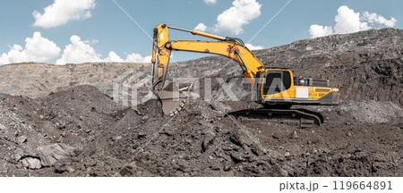 Large quarry dump excavator. Big yellow mining excavator at work site. Loading coal into body truck. Mining digger, mining machinery to loading rock. Production useful minerals Large quarry dump excavator. Big yellow mining excavator at work site. Loading coal into body truck. Mining digger, mining machinery to loading rock. Production useful minerals 119664891