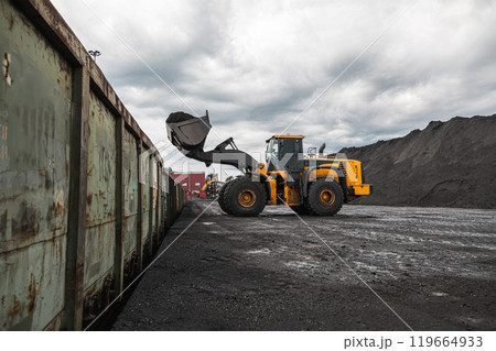 Loading of an loader into railway wagons. Excavator loading coal into wagons. Loading of coal truck using excavator. Shipment coal for transportation by rail 119664933