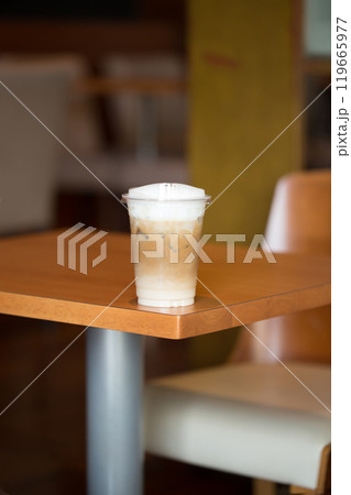 A refreshing Iced Cappuccino sits on a wooden table. 119665977