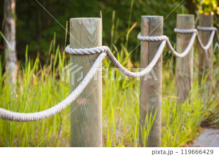Closeup of fence made of rope and wooden pole in park Closeup of fence made of rope and wooden pole in park 119666429