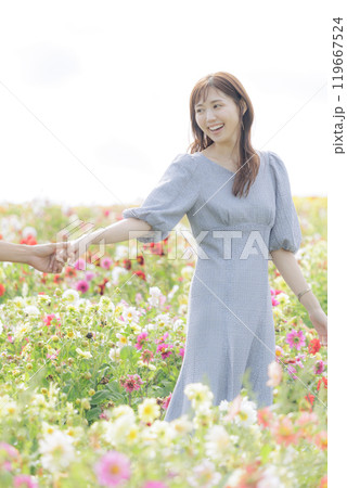 手を繋いで花畑を歩くカップル 119667524