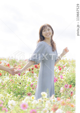 手を繋いで花畑を歩くカップル 119667529