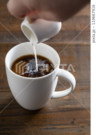 白いカップに入ったコーヒーにコーヒーフレッシュを注ぐ 白いカップに入ったコーヒーにコーヒーフレッシュを注ぐ 119667916