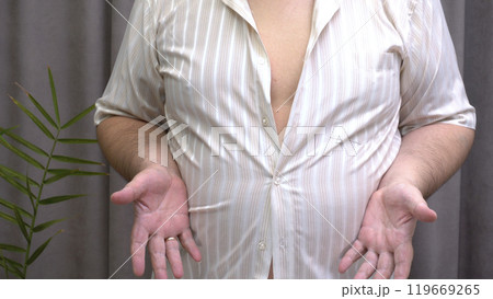 Man Showing that His Shirt Doesn't Fit Over Stomach - Concept of Overweight and Obesity 119669265