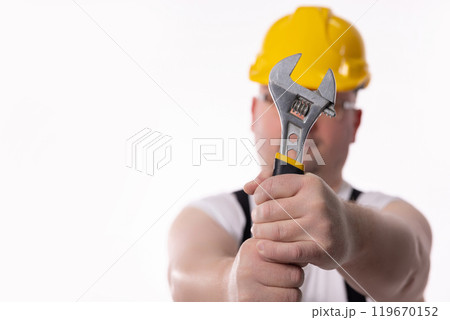 A diligent worker uses an adjustable wrench, dressed in proper safety gear for the job 119670152