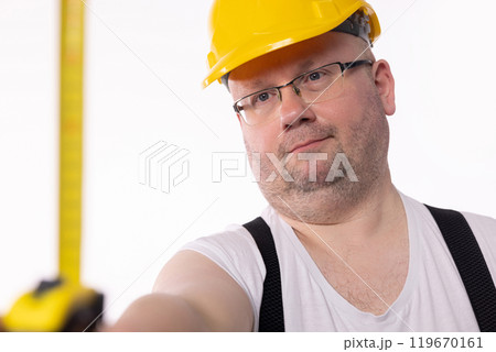 A Construction Worker is carefully Measuring with a Tape Measure in a busy environment 119670161