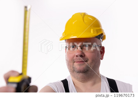 A dedicated Construction Worker with a Measuring Tape and Safety Gear exemplifies diligence 119670173