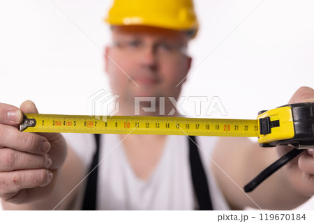 A construction worker diligently using a measuring tape with incredible focus and precision 119670184
